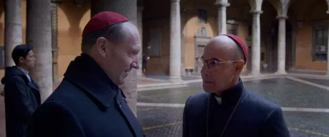 CONCLAVE: Ralph Fiennes (Cardeal Lawrence no filme. Lomeli no livro) e Stanley Tucci (Cardeal Aldo Bellini)